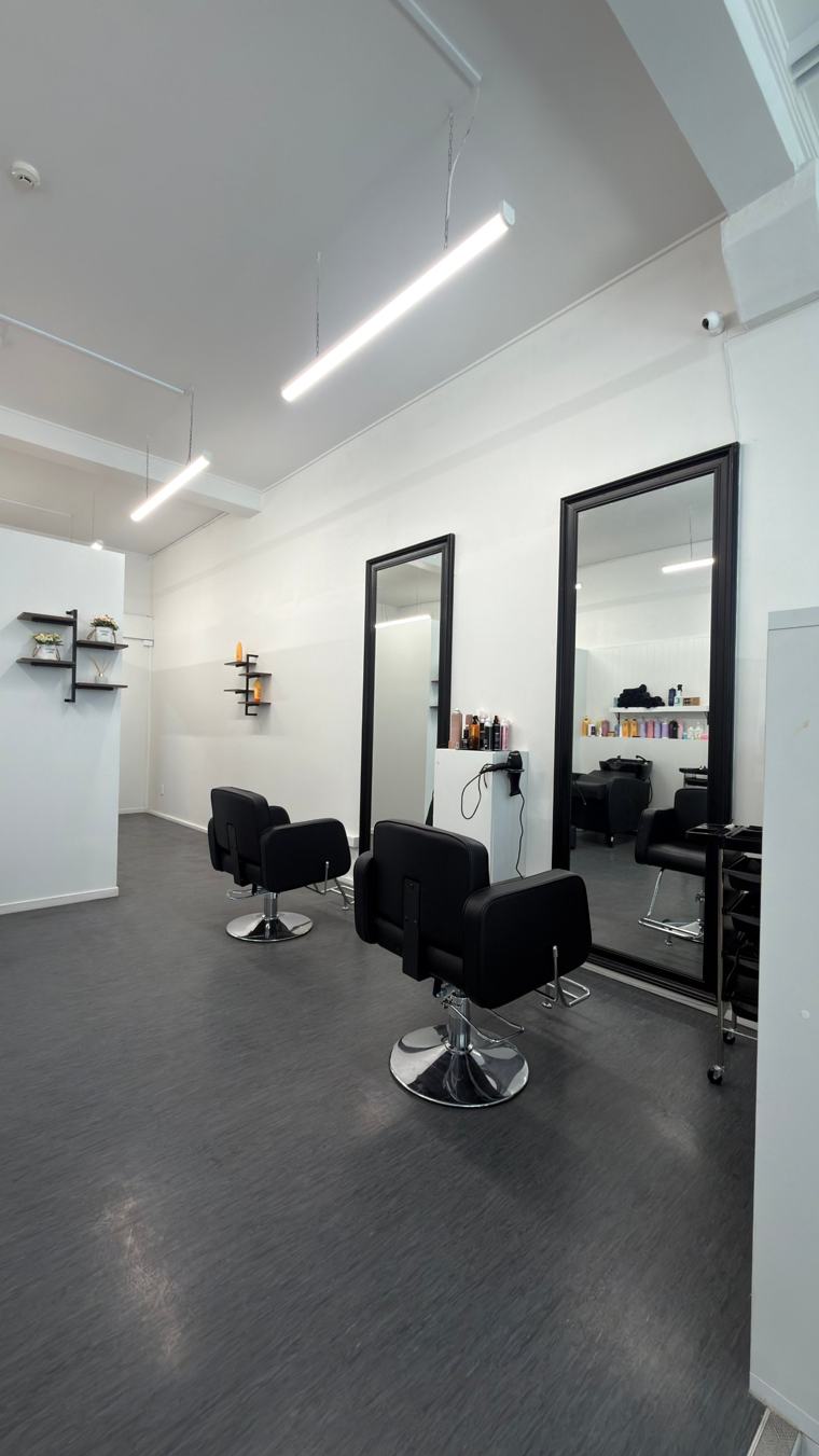 Two styling chairs in front of large black-framed mirrors
