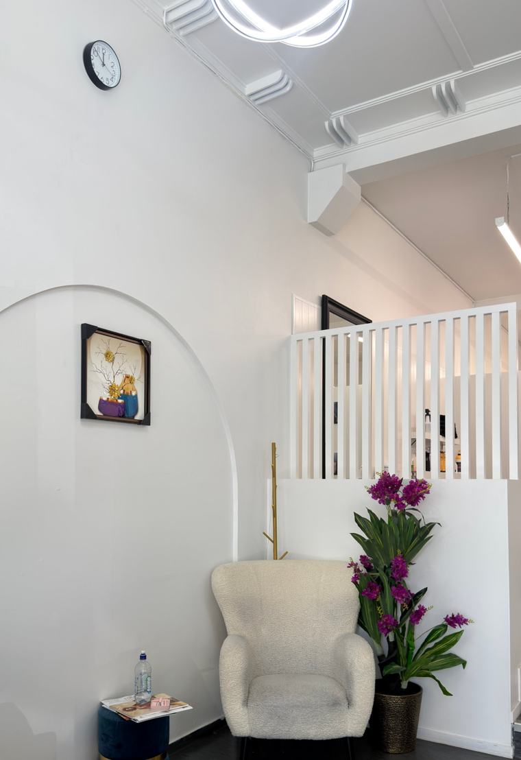 Waiting area with a cream armchair, orchids and an arched feature wall