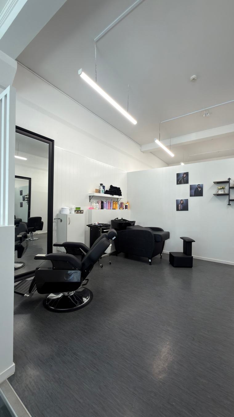 Salon floor with a reclining chair, backwash basin and framed hair portraits